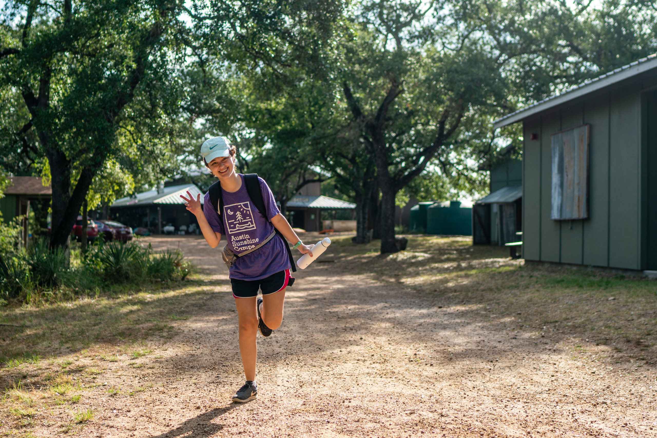 Campista saludando a la cámara en el campamento de verano Lake Travis de Austin Sunshine Camp