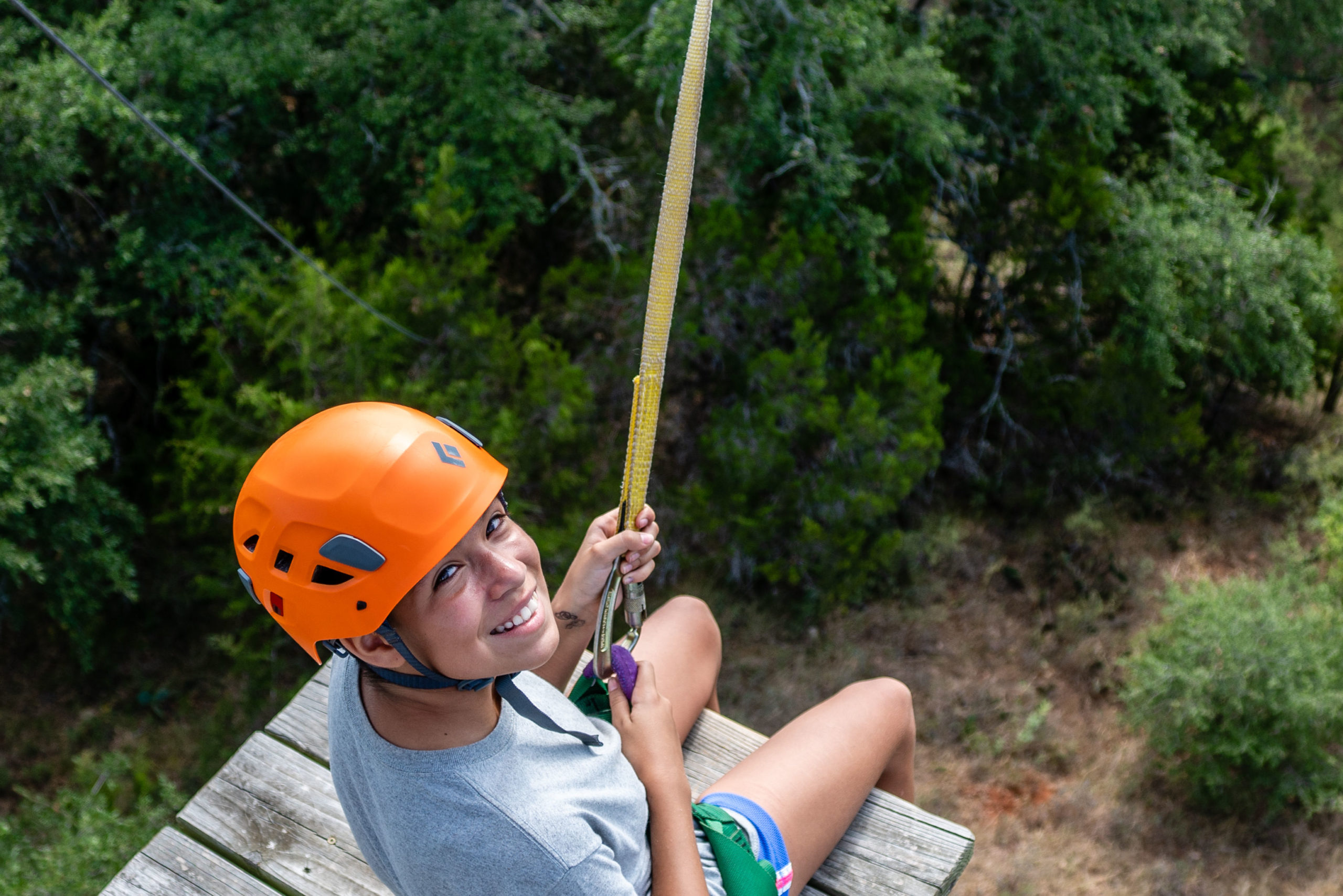 El campista de Austin Sunshine Camps está a punto de subirse a la tirolesa en el campamento de verano de Lake Travis