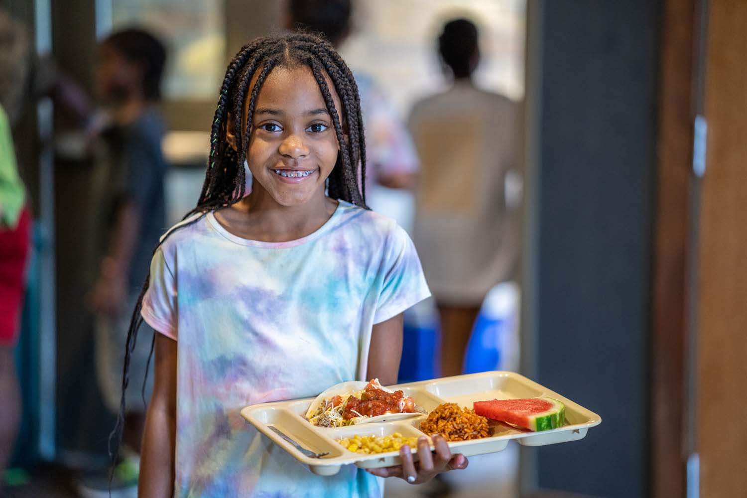 Niña llevando una bandeja de comida.